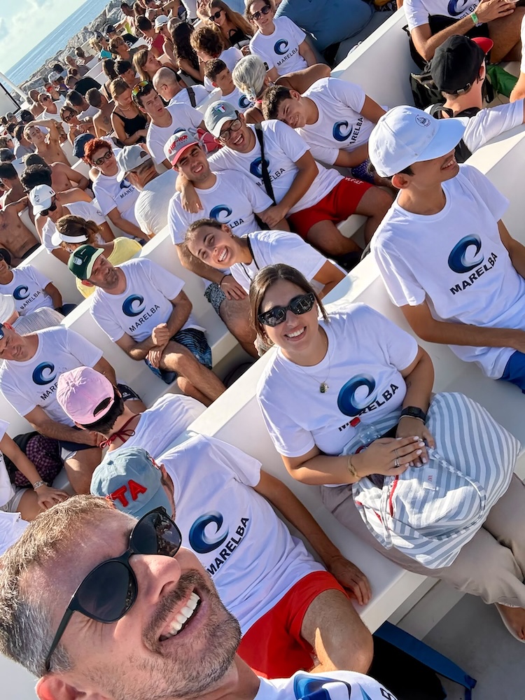 Selfie di gruppo a bordo della barca durante l’escursione a Pianosa, con i partecipanti in maglietta Icaro e cappellino bianco, Marelba 2026
