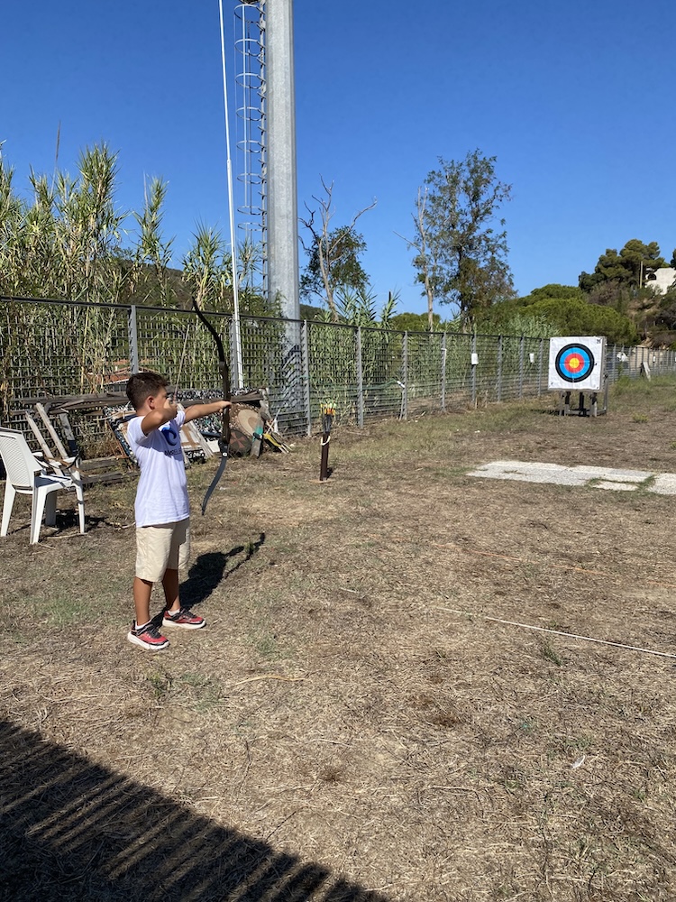 Un bambino tende l’arco mirando al bersaglio nel campo all’aperto durante Marelba 2026